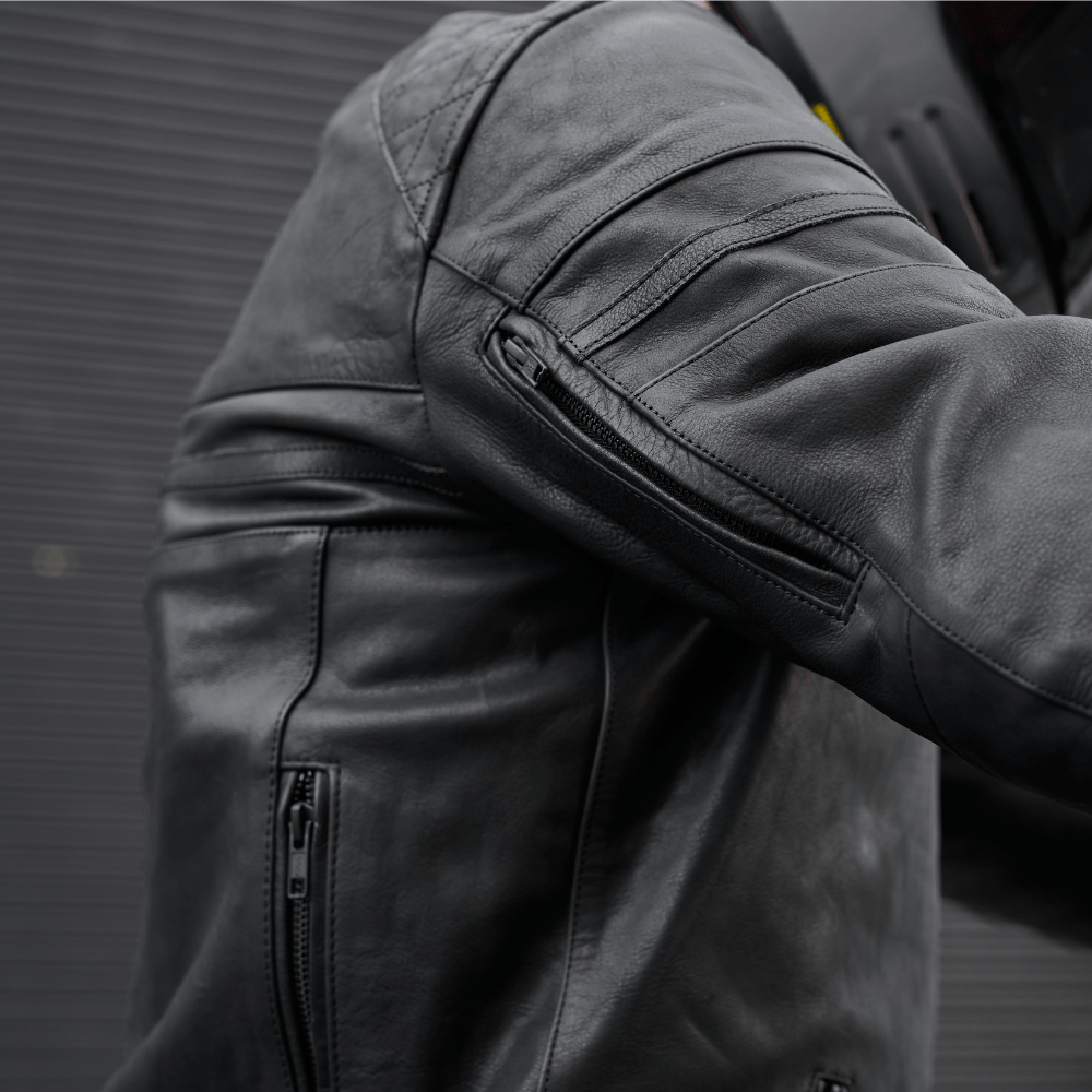 Close-up of a black leather jacket with zippers on a dark background