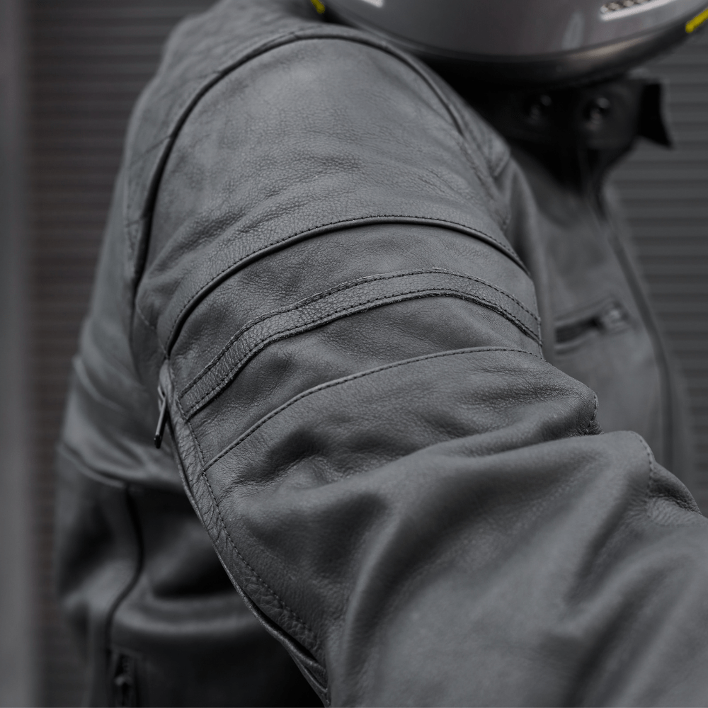 Close-up of a person wearing a dark gray motorcycle jacket with a blurred background