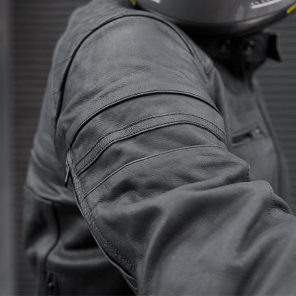 Close-up of a person wearing a dark gray motorcycle jacket with a blurred background
