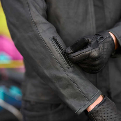 Close-up of a person wearing black gloves and a dark jacket with a colorful background.