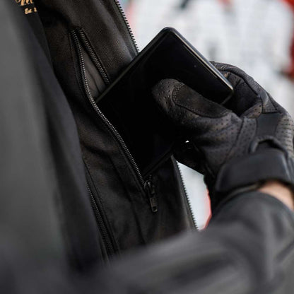 Person wearing black gloves holding a smartphone with a blurred background